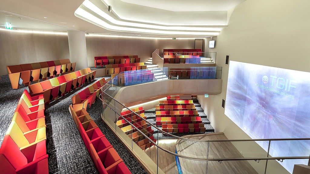 A room with red chairs and a screen.